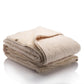Reversible blanket with one side in soft cream organic cotton quilted with wool padding and the other side in natural beige merino wool, shown folded to highlight both textures.